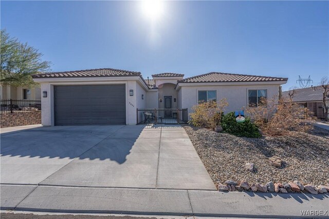 view of front of property featuring a tile roof, stucco siding, fence, a garage, and driveway