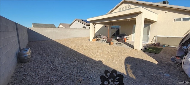 rear view of property with stucco siding, a fenced backyard, and a patio