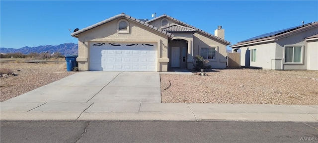 view of front facade featuring an attached garage, a mountain view, concrete driveway, a tiled roof, and stucco siding