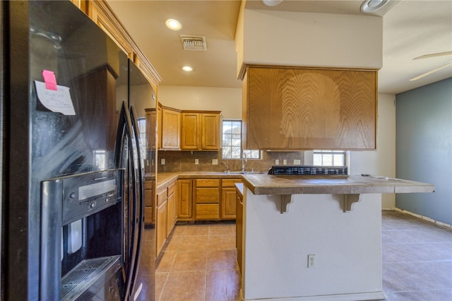 2230 Diamond Creek Rd, Bullhead City, AZ 86442 - kitchen with black fridge with ice dispenser, light tile patterned floors, a kitchen breakfast bar, backsplash, and recessed lighting