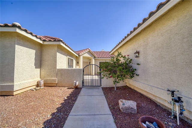 2230 Diamond Creek Rd, Bullhead City, AZ 86442 - view of exterior entry with a gate, stucco siding, and a tile roof