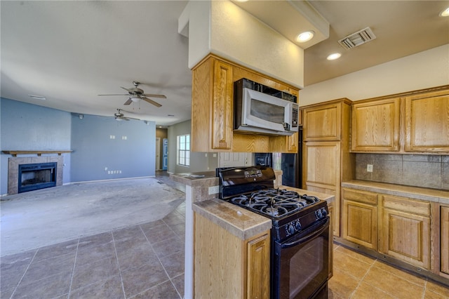 2230 Diamond Creek Rd, Bullhead City, AZ 86442 - kitchen featuring black gas range oven, stainless steel microwave, decorative backsplash, ceiling fan, and light tile patterned floors