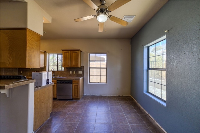 2230 Diamond Creek Rd, Bullhead City, AZ 86442 - kitchen with stainless steel dishwasher, tasteful backsplash, brown cabinetry, a ceiling fan, and dark tile patterned flooring