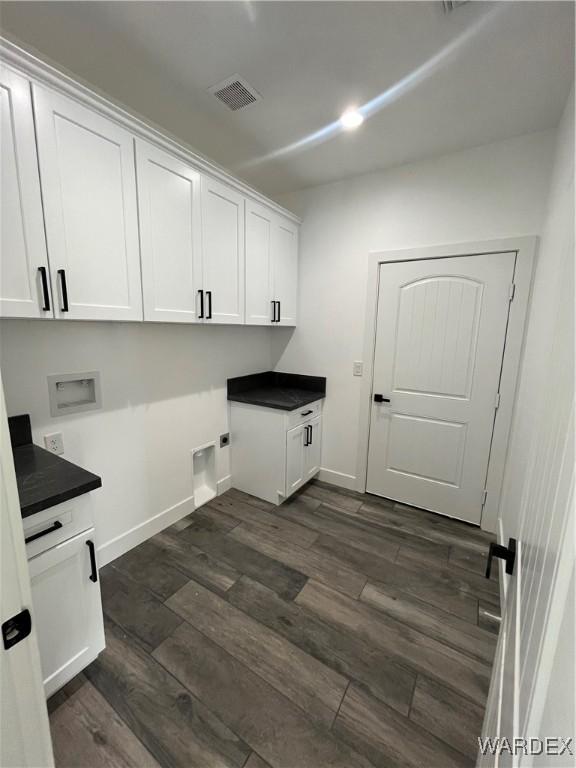 washroom with hookup for a washing machine, visible vents, baseboards, cabinet space, and dark wood finished floors