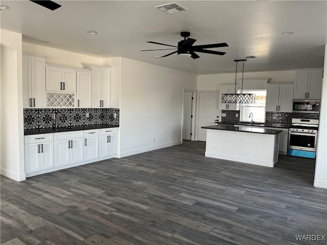 kitchen with appliances with stainless steel finishes, dark countertops, white cabinets, and visible vents