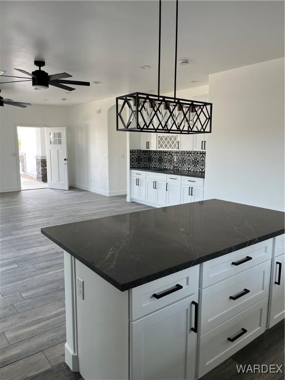 kitchen with a center island, dark stone counters, white cabinets, and decorative light fixtures