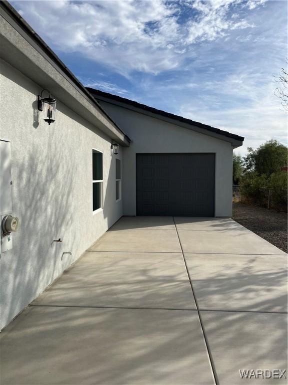 view of side of home featuring a garage, driveway, and stucco siding