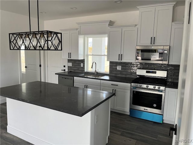 kitchen with appliances with stainless steel finishes, a center island, white cabinets, and a sink