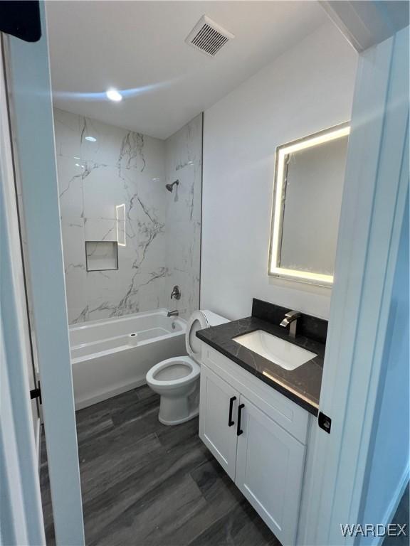 full bath with shower / tub combination, toilet, wood finished floors, vanity, and visible vents