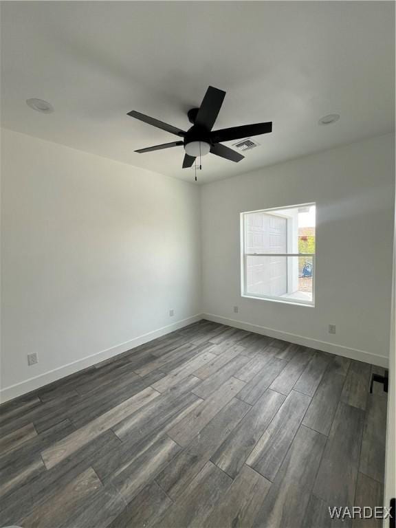 unfurnished room featuring visible vents, dark wood finished floors, baseboards, and ceiling fan