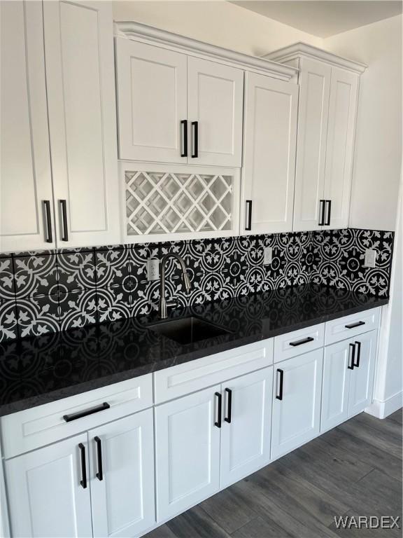 kitchen featuring dark wood-type flooring, a sink, white cabinetry, and decorative backsplash