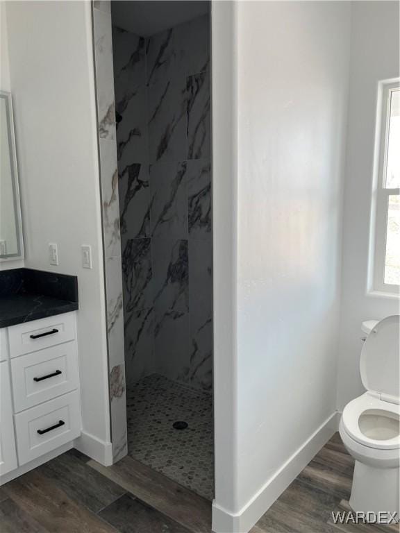 full bathroom with toilet, wood finished floors, vanity, baseboards, and a marble finish shower