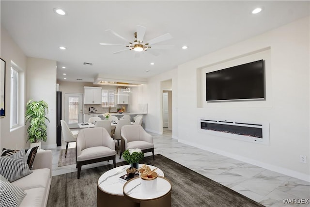 living room with a glass covered fireplace, marble finish floor, visible vents, and recessed lighting