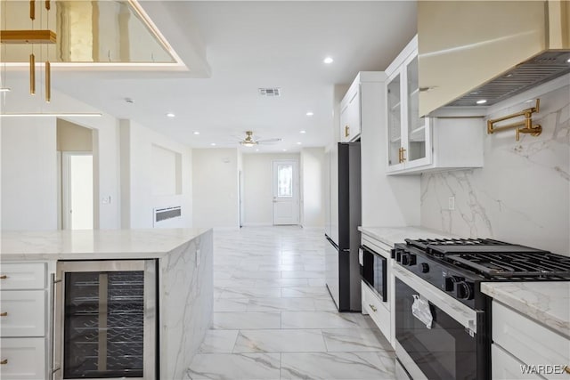 kitchen featuring light stone counters, wine cooler, black gas range, white cabinetry, and glass insert cabinets