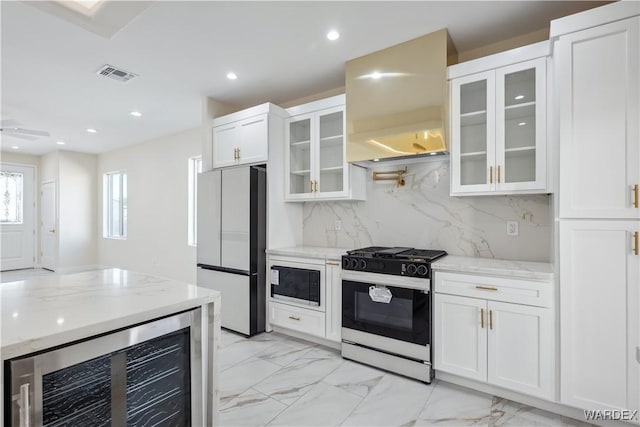 kitchen with range with gas stovetop, beverage cooler, glass insert cabinets, and stainless steel refrigerator