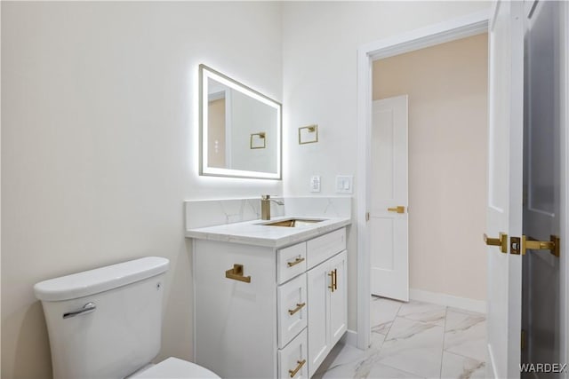 half bath featuring toilet, marble finish floor, baseboards, and vanity