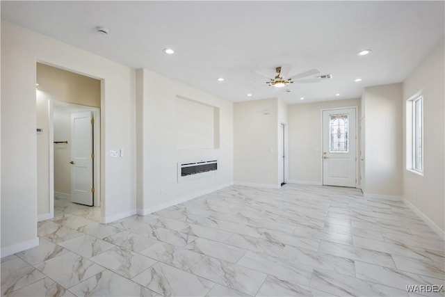 unfurnished living room with a glass covered fireplace, marble finish floor, baseboards, and recessed lighting