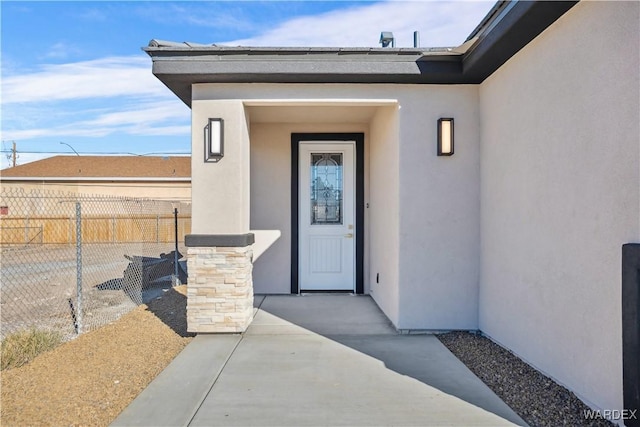 doorway to property featuring a patio, fence, and stucco siding