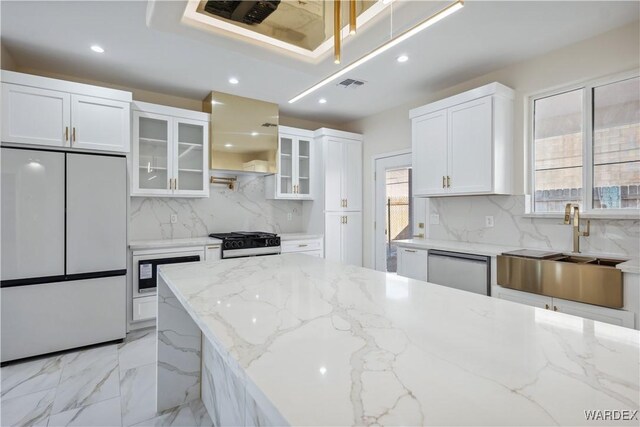 kitchen featuring gas range oven, stainless steel dishwasher, glass insert cabinets, white cabinets, and fridge