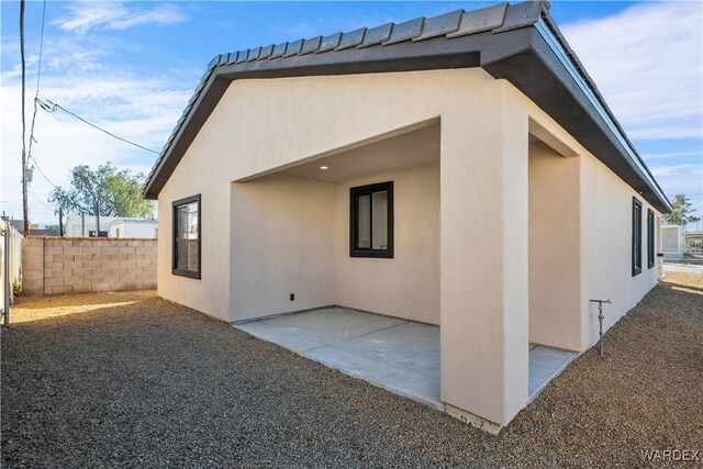 view of property exterior featuring stucco siding, fence, and a patio