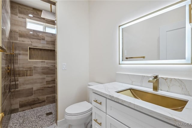 full bathroom featuring toilet, tiled shower, and vanity