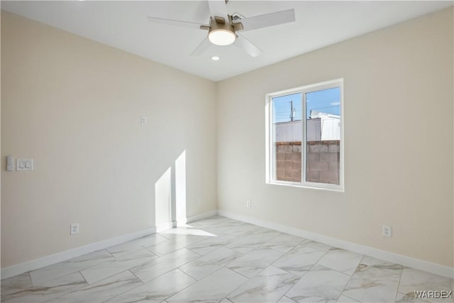 spare room featuring marble finish floor, ceiling fan, and baseboards