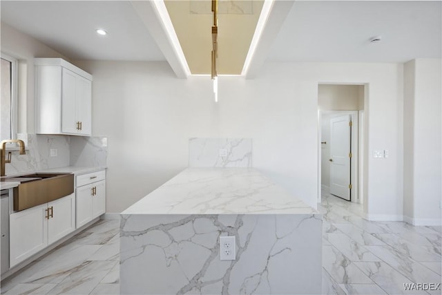 kitchen with marble finish floor, light stone counters, white cabinets, and a sink