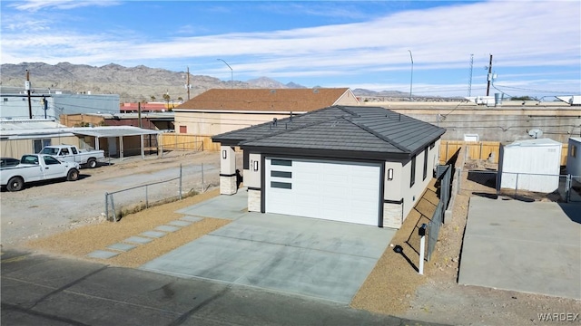 view of front of house with stucco siding, fence, a mountain view, and an outbuilding