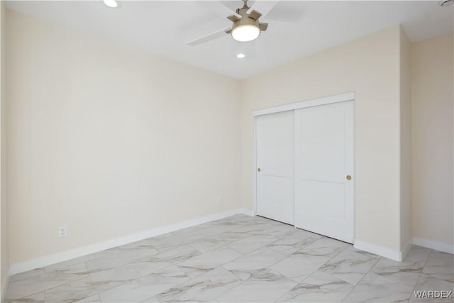 unfurnished bedroom with marble finish floor, a closet, recessed lighting, and baseboards