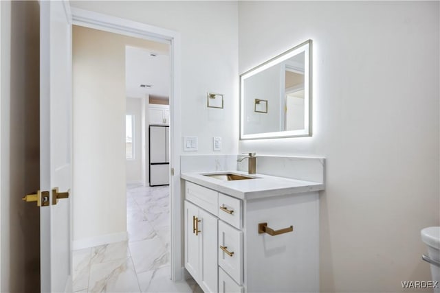 half bathroom featuring marble finish floor, vanity, and baseboards