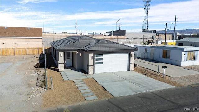 view of front facade featuring stucco siding, an attached garage, fence, driveway, and a tiled roof