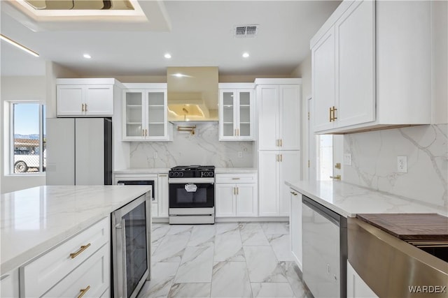 kitchen with refrigerator, gas range oven, glass insert cabinets, freestanding refrigerator, and white cabinets