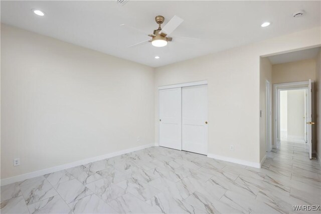 unfurnished bedroom with recessed lighting, a closet, marble finish floor, and baseboards