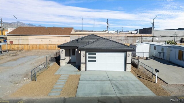 view of front of home with a garage, a tiled roof, fence private yard, a mountain view, and stucco siding