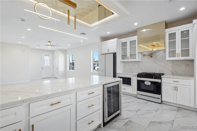 kitchen featuring refrigerator, gas range oven, glass insert cabinets, white cabinetry, and beverage cooler