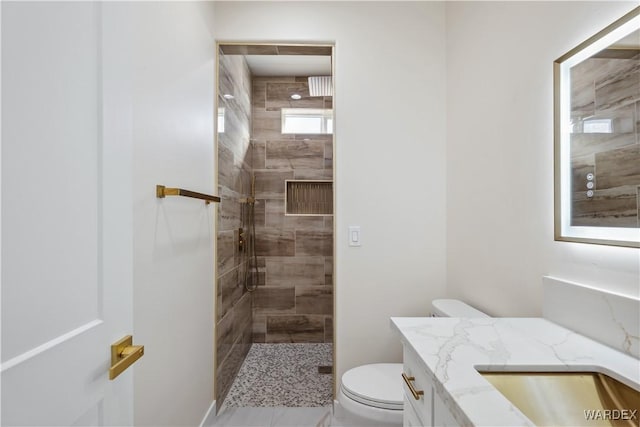 bathroom with a stall shower, vanity, and toilet