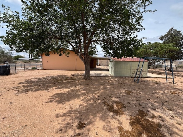 view of yard featuring central AC unit, a shed, fence, and an outbuilding