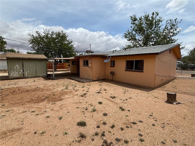 rear view of house featuring an outdoor structure, a shed, brick siding, and fence