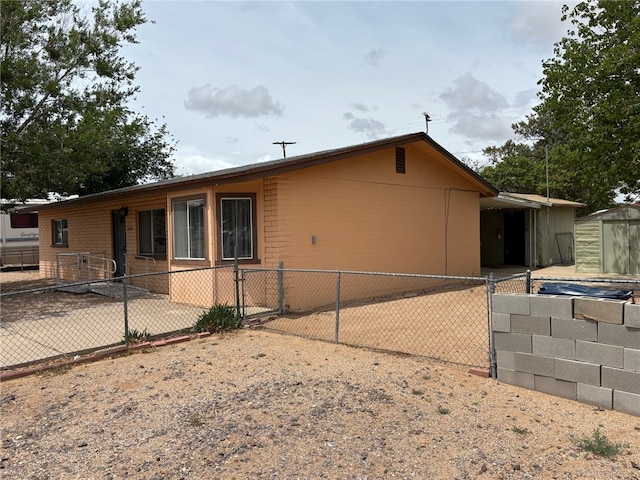 view of side of home featuring an outbuilding, a storage shed, fence, and a gate