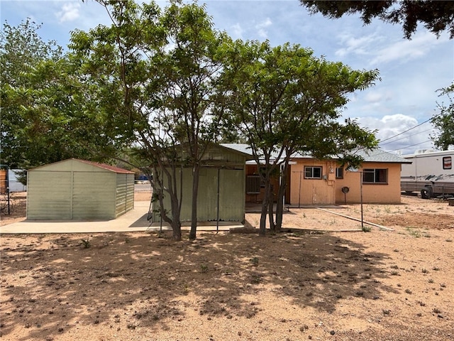 back of house with fence, a shed, and an outbuilding