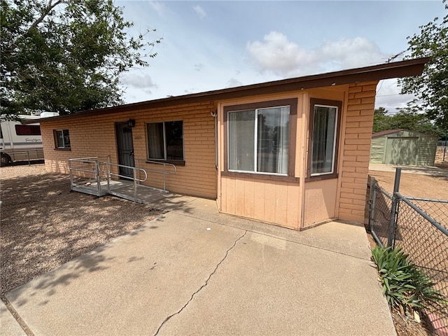 back of property with a patio, an outdoor structure, fence, and a storage unit