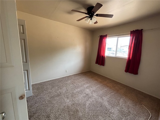 carpeted empty room featuring ceiling fan and baseboards