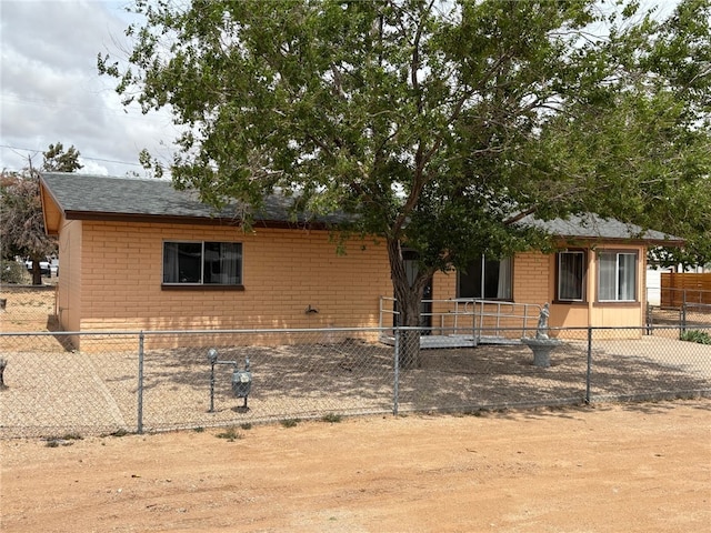 view of front of home featuring a shingled roof, a fenced front yard, and brick siding