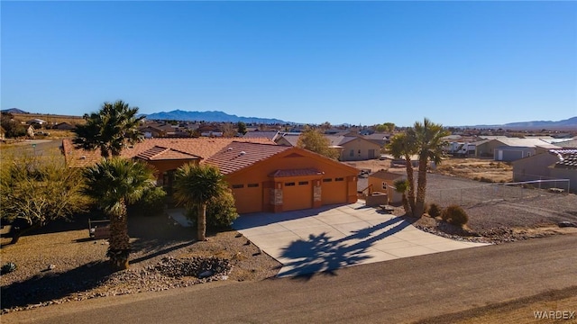 view of front of house featuring a mountain view, a garage, a tile roof, driveway, and a residential view