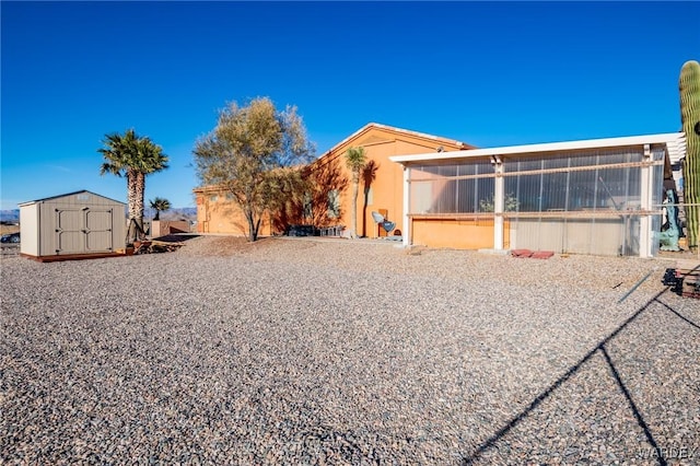 back of property with a sunroom, an outdoor structure, and a storage unit