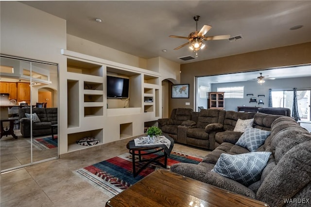 living area featuring arched walkways, ceiling fan, light tile patterned flooring, and visible vents