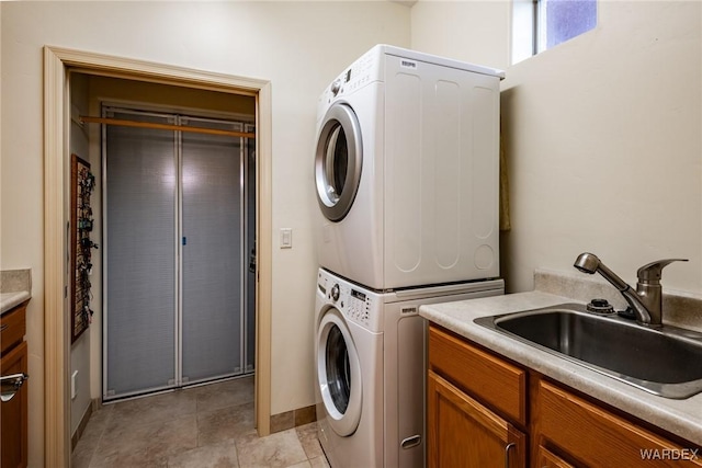 laundry room featuring cabinet space, a sink, and stacked washing maching and dryer