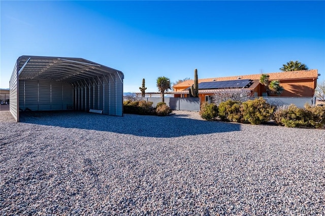 exterior space featuring gravel driveway, fence, and a carport