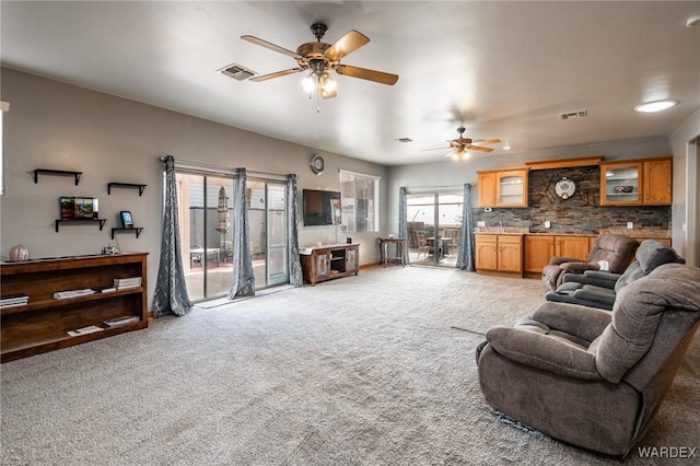 living area featuring a ceiling fan, visible vents, and light carpet