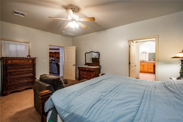 carpeted bedroom with visible vents, ceiling fan, and ensuite bath